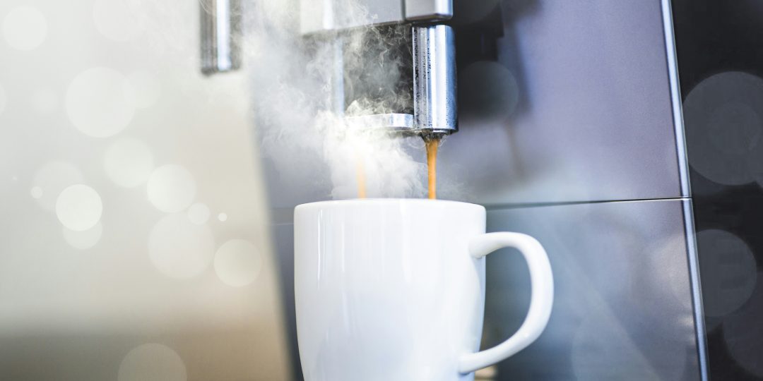 Cappuccino machine pouring coffee into a white mug