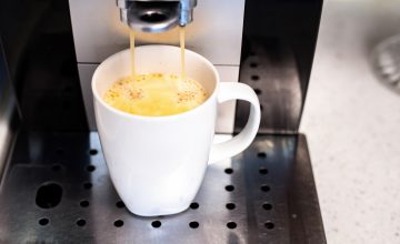 Freshly brewed coffee pours from a sleek modern coffee machine