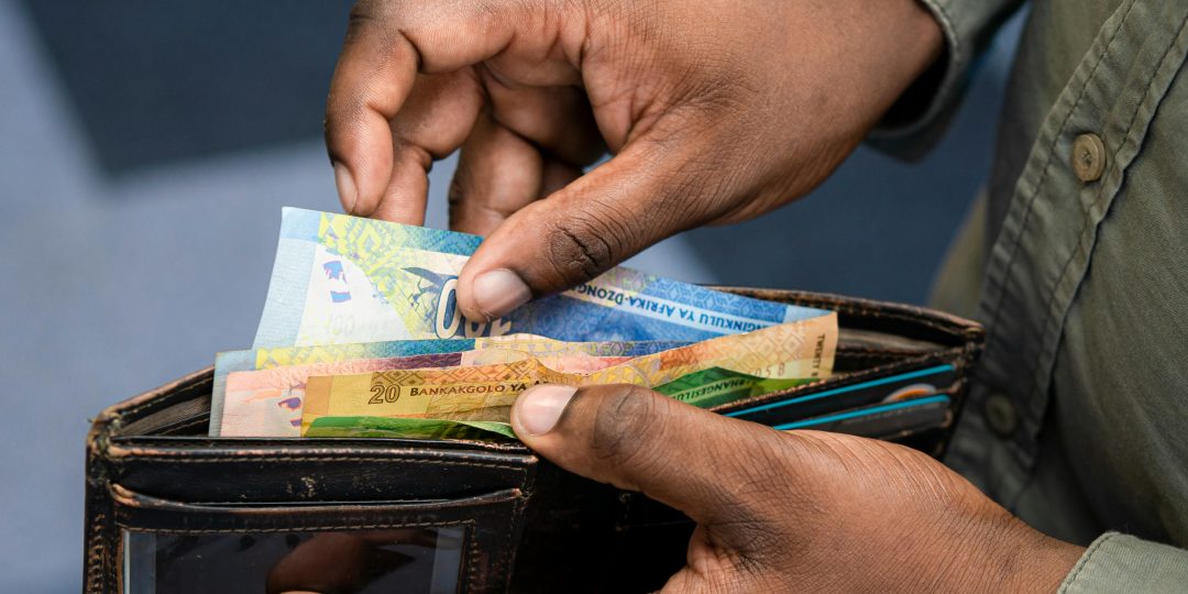 Male hand taking out hundred rand from a wallet